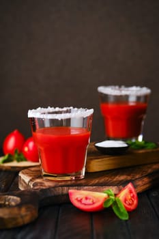 Closeup view of glass with salty tomato juice on dark wooten table