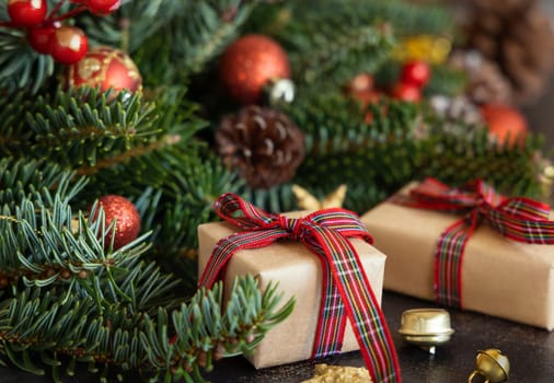 Wrapped gift boxes between Christmas decorations, pine cones and green fir branches close up. Christmas or New Year Holiday atmosphere flat lay