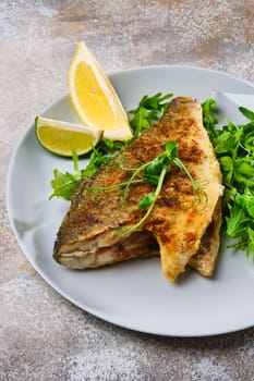 Close up view od fried dorada fish with fresh arugula