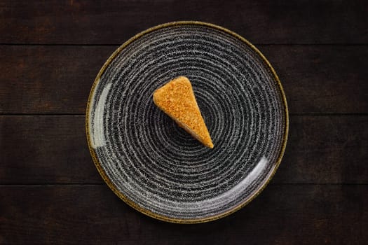Top view of plate with piece of honey cake on wooden background