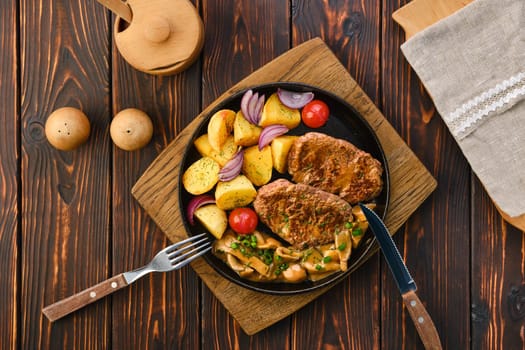 Plate with fried pork fillet, potato wedges, mushrooms and tomato