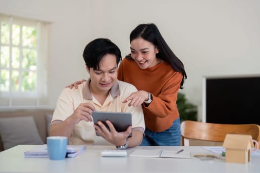 A couple shares excitement over their financial plans while reviewing information on a tablet at home.