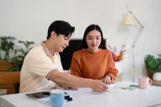 A couple collaborates on financial planning at home, reviewing bills and discussing budgeting strategies.