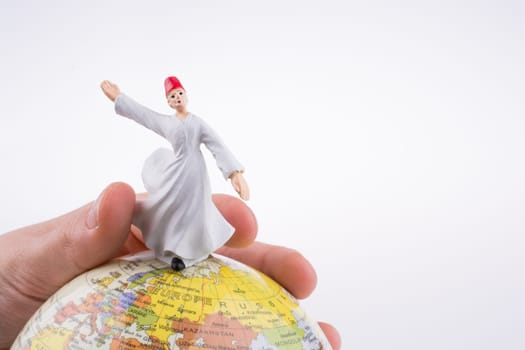 Hand holding a Sufi Derviş on a globe