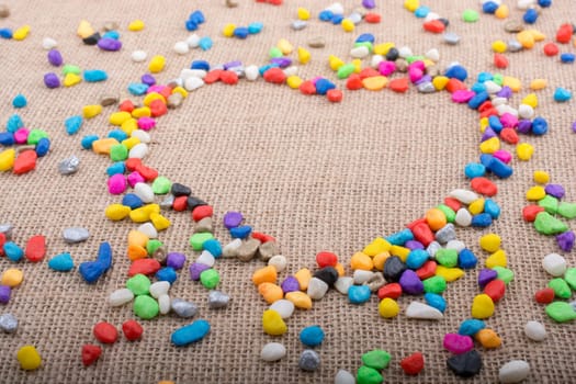 Colorful little pebbles form a heart shape on canvas ground