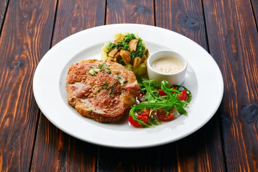 Fried chop pork cutlet with mashed potato and boletus edulis gravy served with fresh tomato cherry and arugula