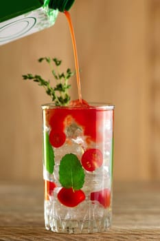 Pouring tomato juice to cocktail with vodka, mint and ice
