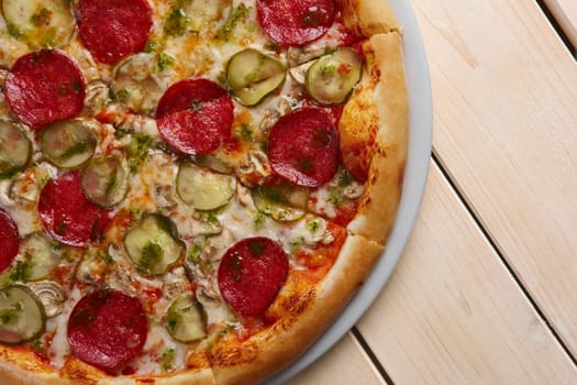 Top view of piece of pizza with sausage, cucumber and mushrooms