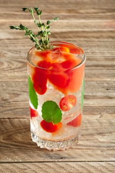 Cocktail with vodka, tomato, mint and ice cubes on wooden table