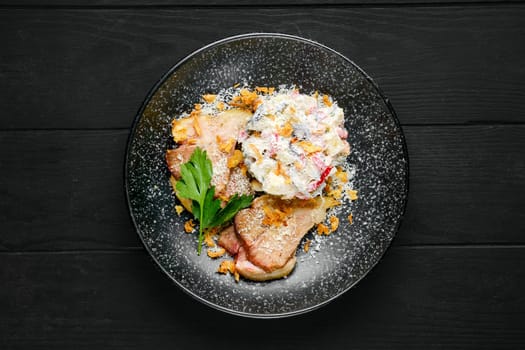 Overhead view of fried ham with salad sprinkled with bacon chips and grated parmesan on a plate
