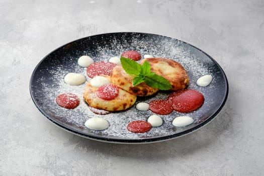 Sweet curd patties with sour cream and strawberry jam on a plate