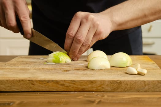Closeup view of cutting onion. Male hands with knife sliceing onion.