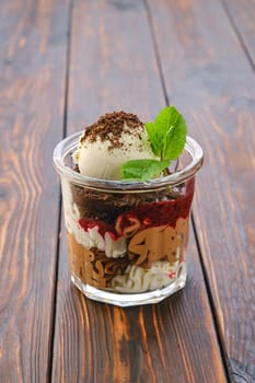 Dessert with cookie crumbs, soft cheese, strawberry jam and ice cream with grated chocolate