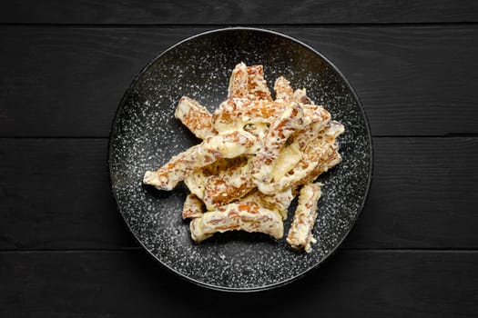 Overhead view of salty bread sticks covered with melted cheese on a plate