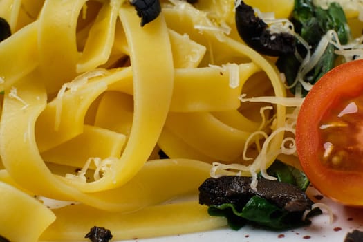 Macro photo with shallow depth of field of pasta with parmesan, chopped olives and basil