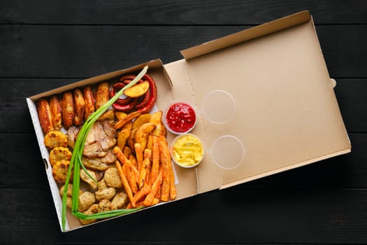 Roasted chicken wings, celery and carrot sticks and sauce in cardboard box