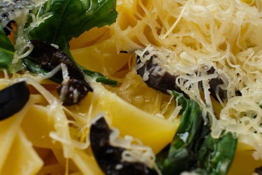 Macro photo with shallow depth of field of pasta with parmesan, chopped olives and basil