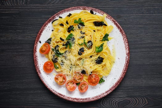Top view of tagliatelle with tomato, parmesan, chopped olives and basil