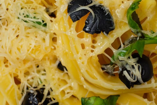 Macro photo with shallow depth of field of pasta with parmesan, chopped olives and basil