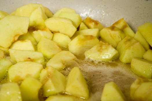 Slices of green apples caramelizing in frying pan with sugar (photo with shallow depth of field)
