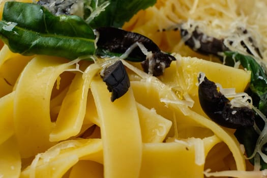 Macro photo with shallow depth of field of pasta with parmesan, chopped olives and basil