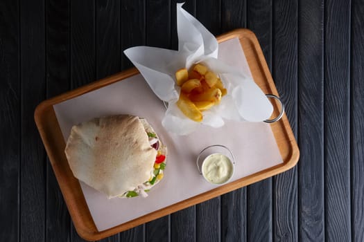 Top view of pita bread with chicken and vegetables served with fried potato
