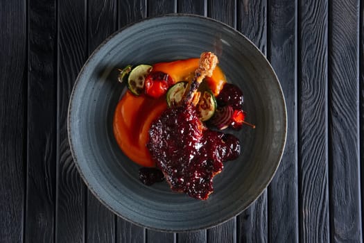 Top view of fried duck thigh with carrot puree and zuccini, pepper and onion on wooden skewer