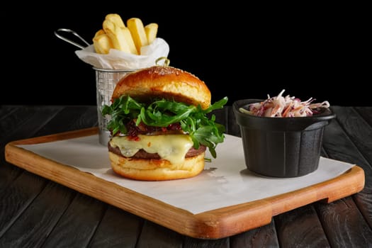 Juicy beef burger with lingonberry sauce, melted cheese, arugula served with fried potato and red cabbage