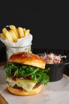 Juicy beef burger with lingonberry sauce, melted cheese, arugula served with fried potato and red cabbage