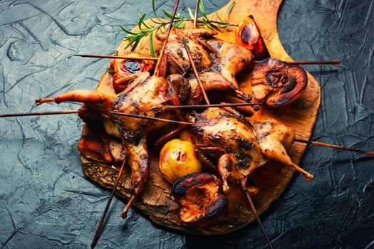 Shish kebab of quail and autumn quince on wooden skewers