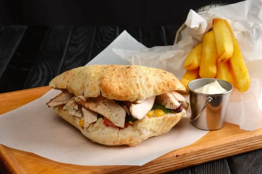 Pita bread with meat, vegetables and fried potato in metal basket and sauce
