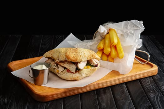 Pita bread with meat, vegetables and fried potato in metal basket and sauce