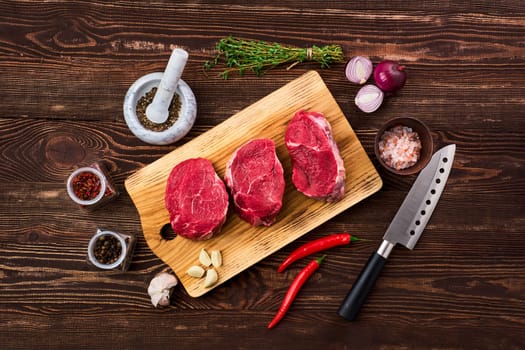 Top view of marinated beef fillet mignon with spice on wooden table