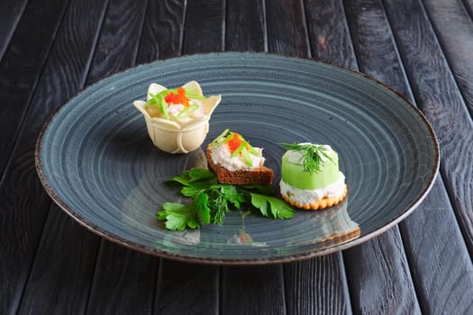 Appetizer for reception. Set of tartlet with mozzarella and caviar, brown bread with fish pate and kiwi stuffed with cream cheese