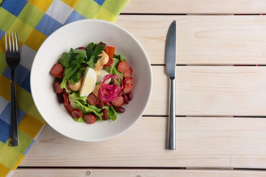 Salad with smoked sausage and egg. Top view of served table