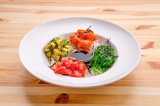 Salmon sashimi rice bowl with avocado, seawed, tomato and soy sauce
