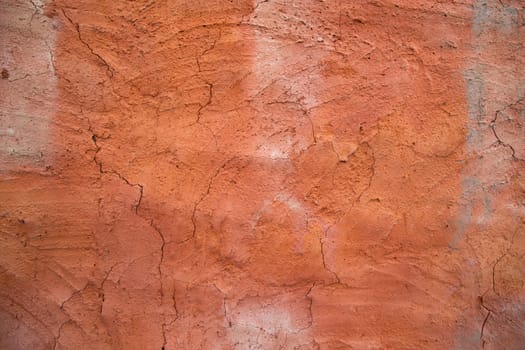 The texture of a red concrete wall with cracks and scratches can be used as a background