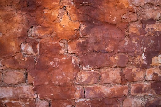 The texture of a red concrete wall with cracks and scratches can be used as a background