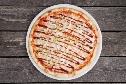 Top view of pizza with chicken barbecue on wooden table.
