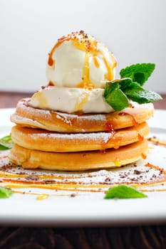 Macro photo of pancakes with ice cream, whipped cream and maple syrup
