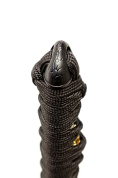 Close up the Kashira: butt cap (or pommel) made of steel on the end of the black silk cord wrapped handle Japanese sword isolated in white background. Selective focus.