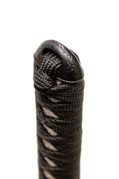 Close up the Kashira: butt cap (or pommel) made of steel on the end of the black silk cord wrapped handle Japanese sword isolated in white background. Selective focus.