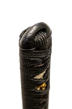 Close up the Kashira: butt cap (or pommel) made of steel on the end of the black silk cord wrapped handle Japanese sword isolated in white background. Selective focus.