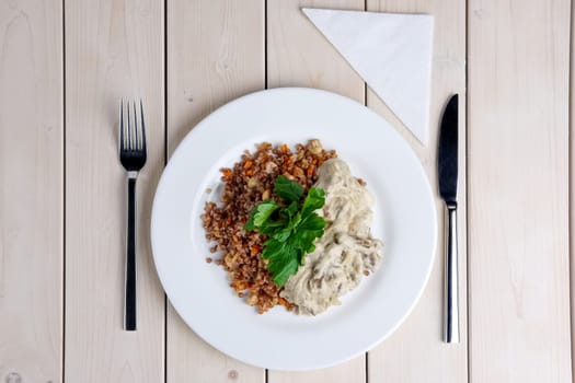 Top view of beef stroganoff with creamy onion sauce and buckwheat with fried mushrooms on served table.