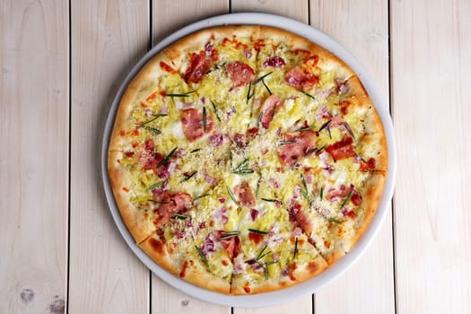Top view of pizza with bacon chips, ham, cheese and rosemary