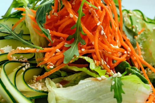 Macro photo of salad with cucumber, spicy carrot, arugula and sesame