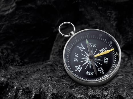 Compass nestled on black coal background. Travel destination and navigation concept