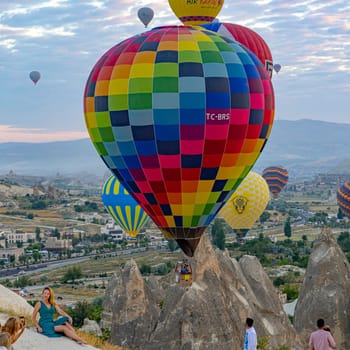 GOREME/TURKEY - June 30, 2022: tourists take pictures with hot air balloons in the background