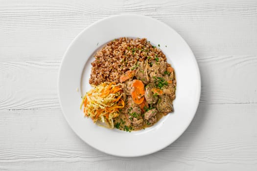 Top view of plate with chicken liver with buckwheat and pickled cabbage salad