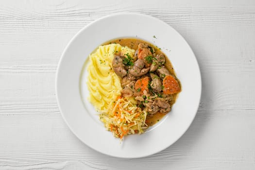 Top view of plate with chicken liver with mashed potato and pickled cabbage salad